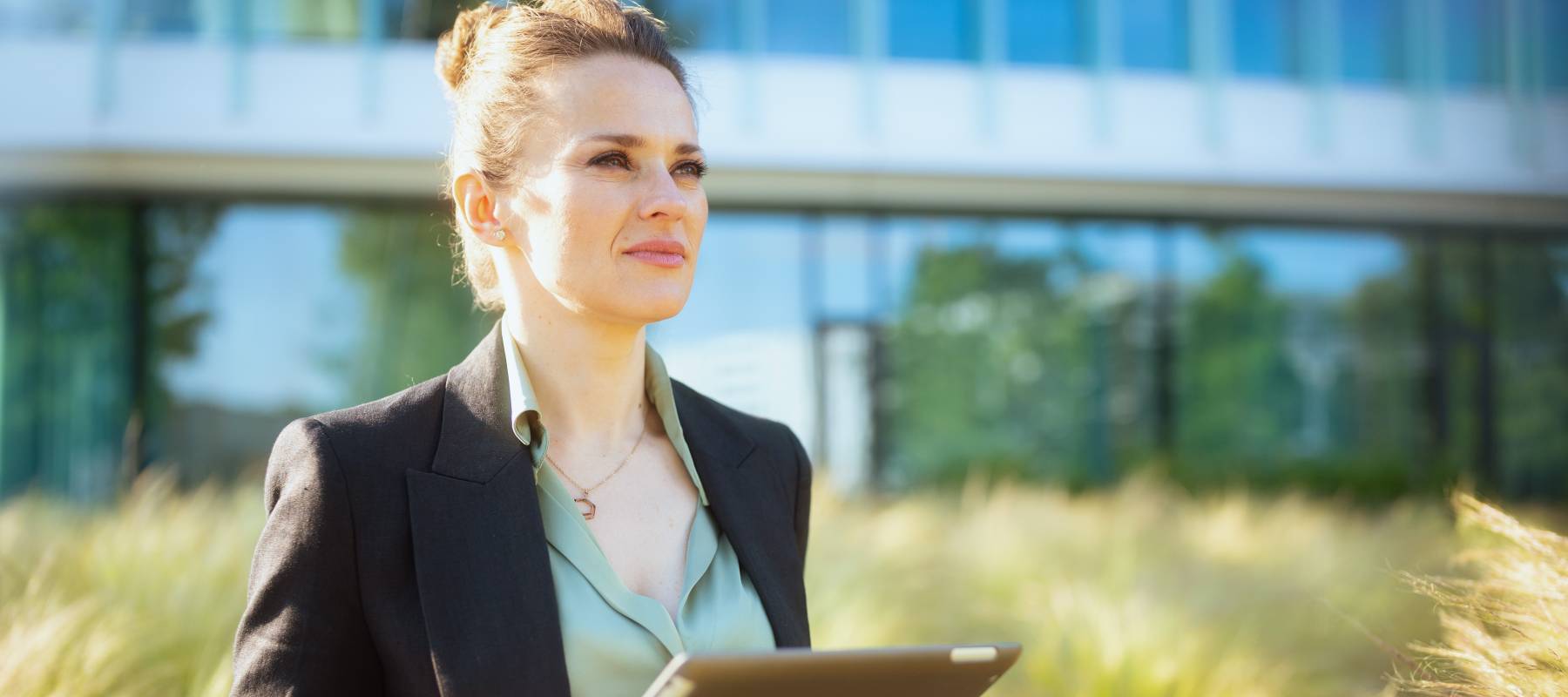 pensive modern female worker in business district in black jacket with digital tablet