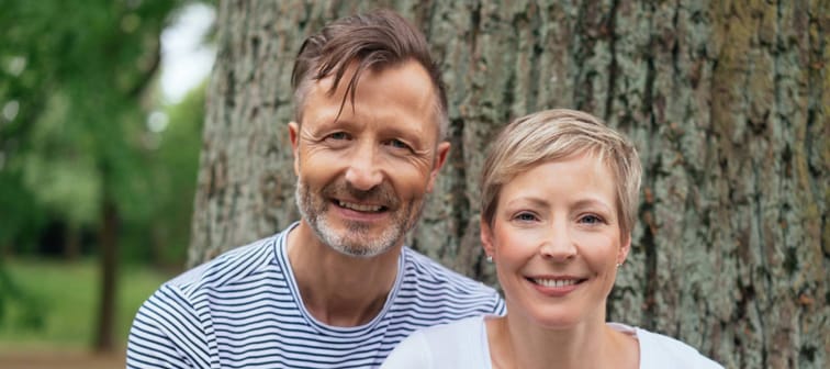 Portrait of a happy middle-age couple looking at camera while posing outdoors in the park.