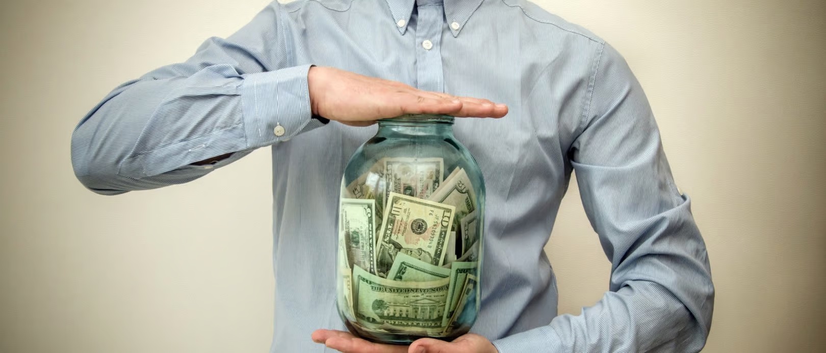 man holding jar of money